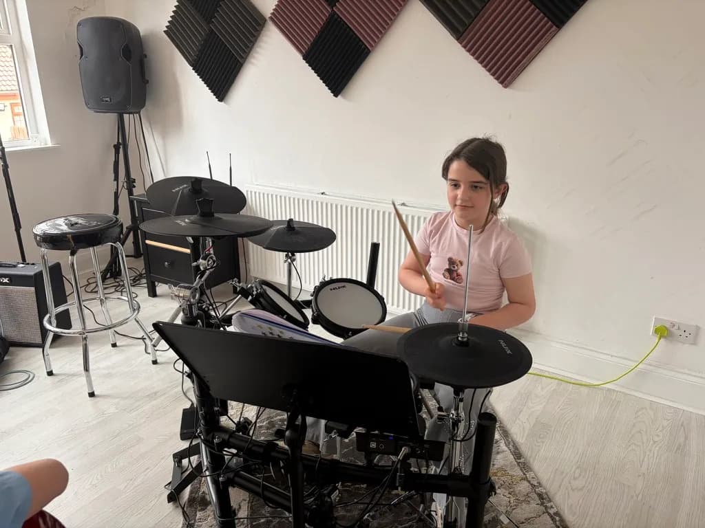 A young student playing the electronic drum kit at Apollo