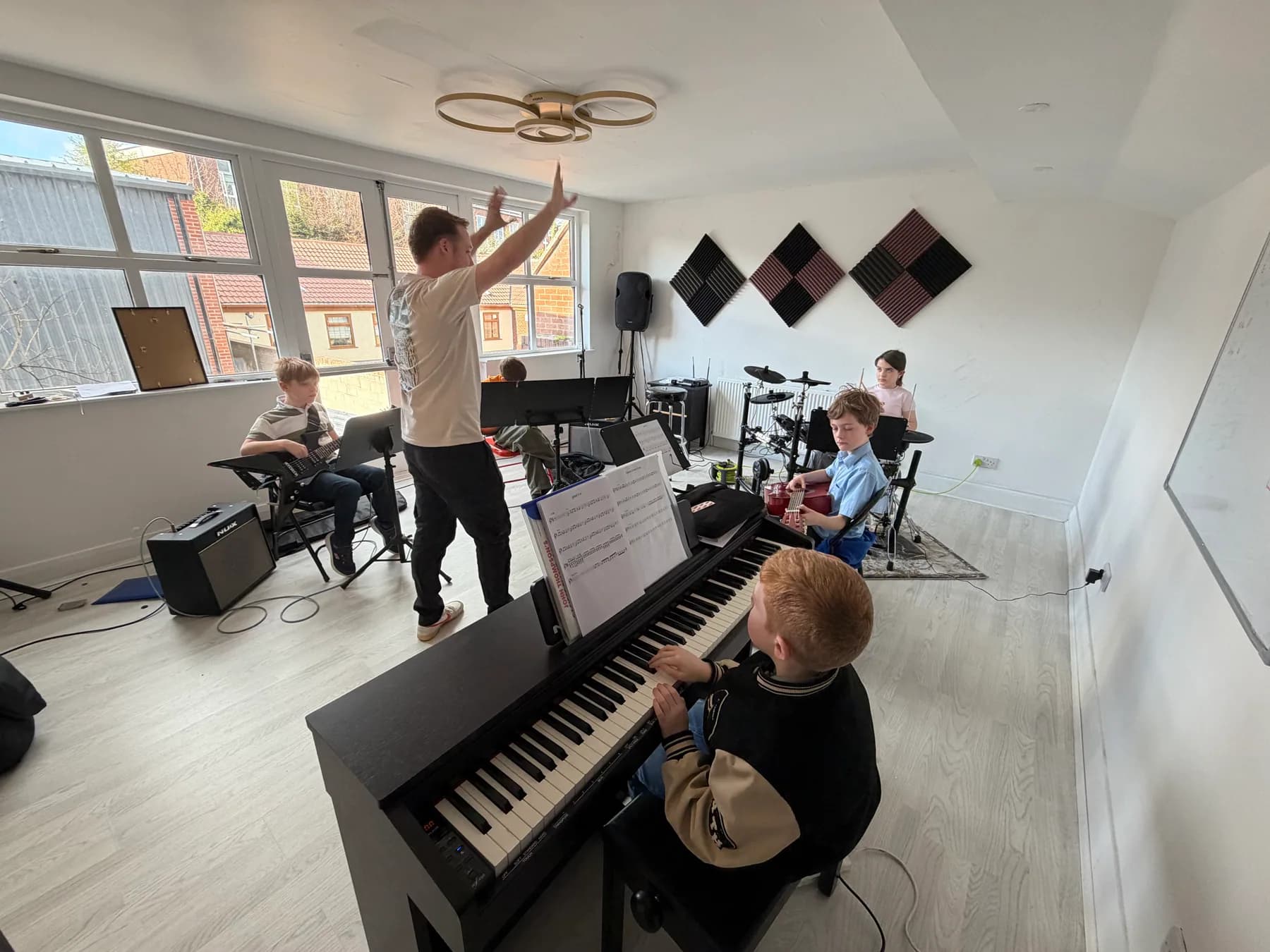 A student band rehearsing together with their teacher at Apollo