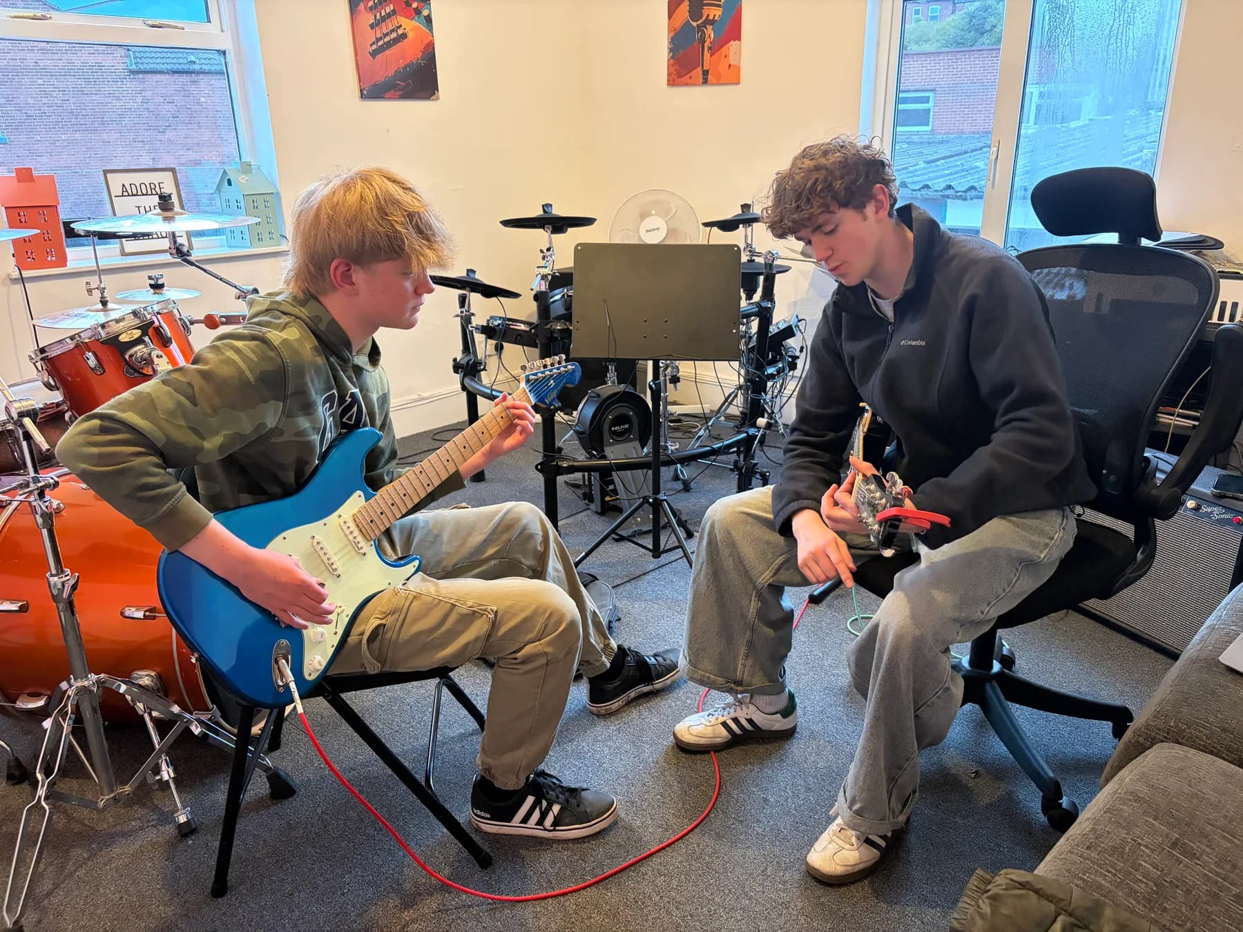 Two musicians learning and playing guitar together at Apollo