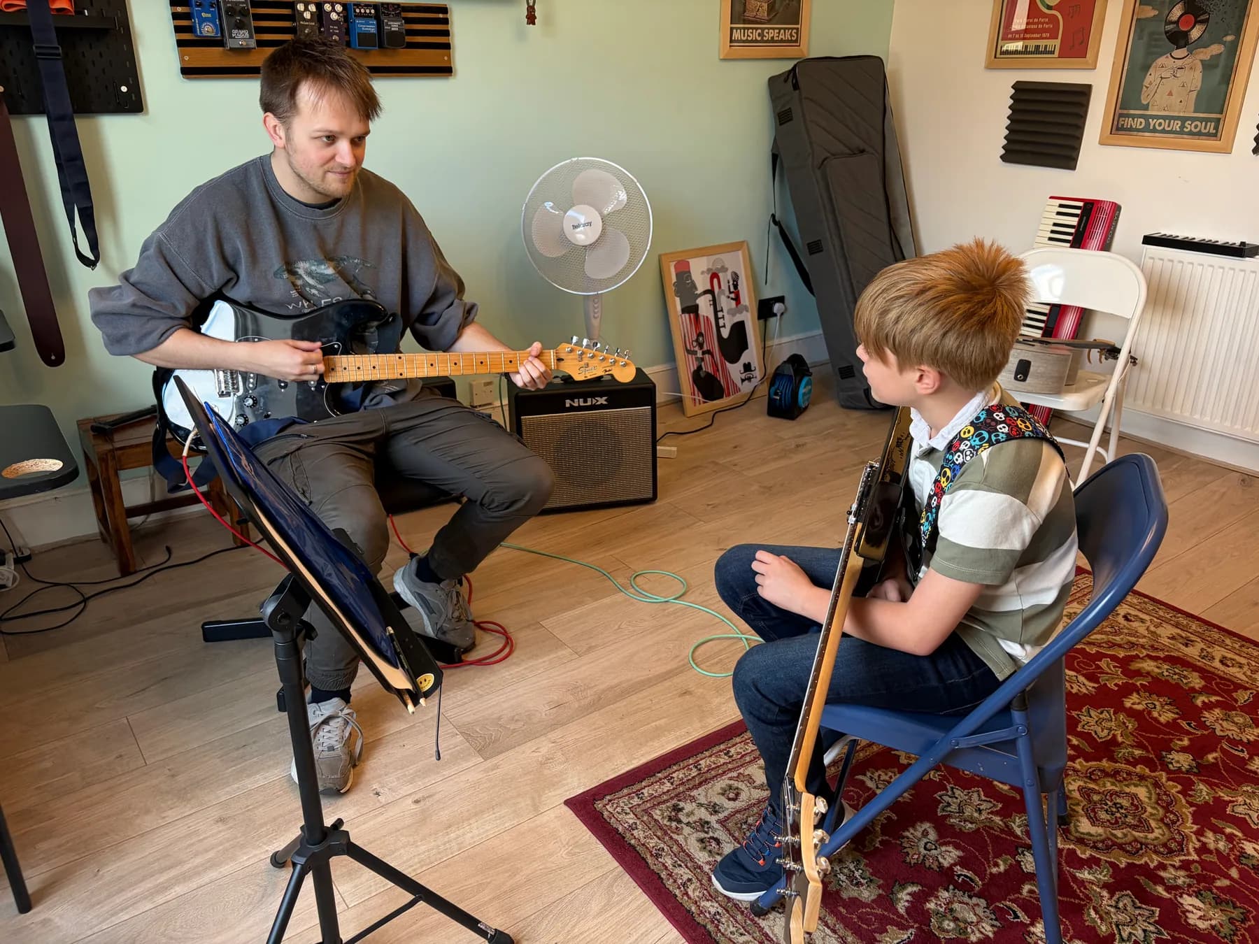 A guitar teacher demonstrating a passage for a young student